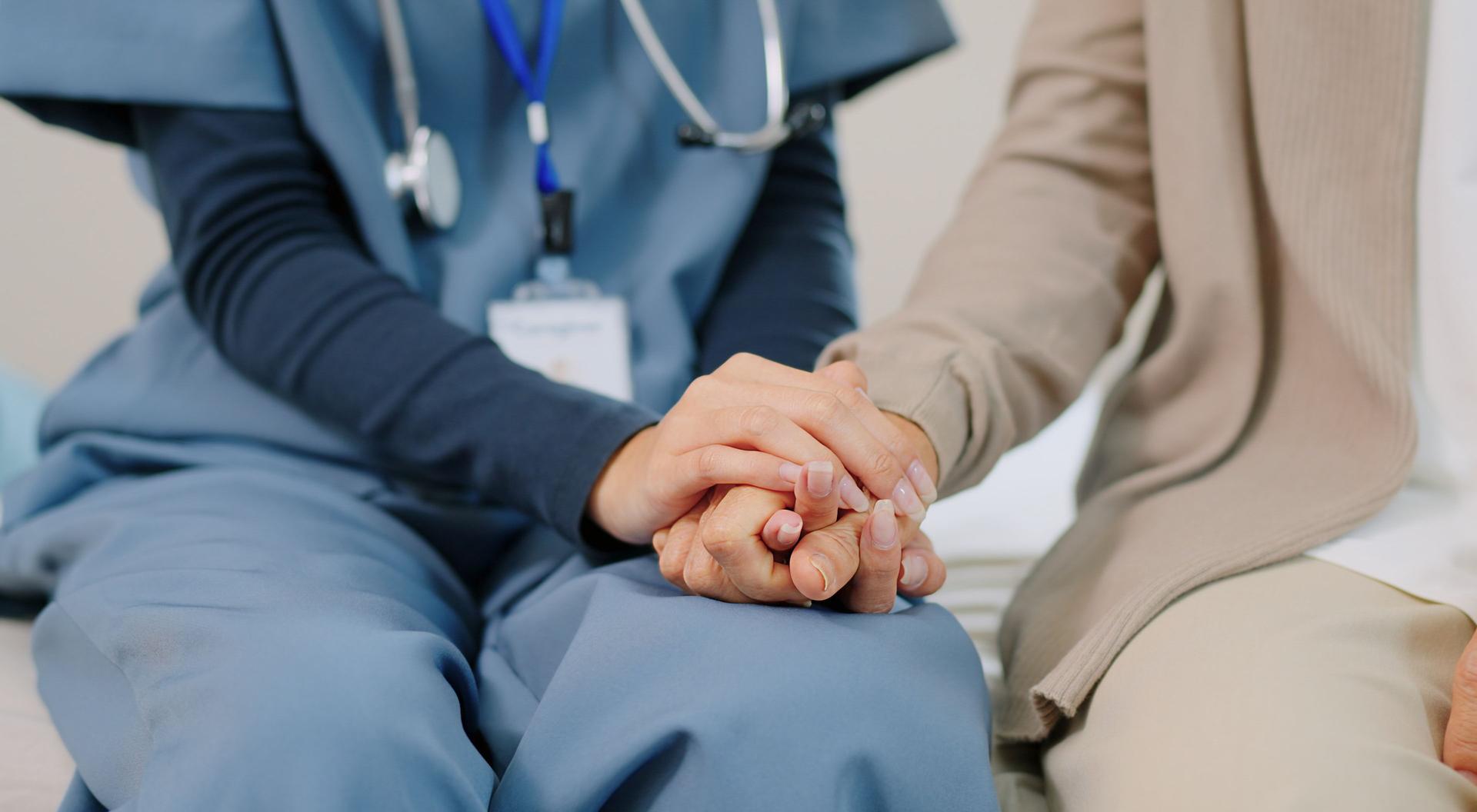 Closed up woman Hand caregiver nurse wearing blue scrubs  holds the hand ,talking with empathy and support consulting to elderly woman retirement being consoled  offering kidness,comfort and touching empathy in mental health